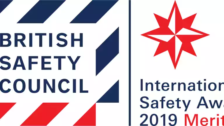 British Safety Council logo next to a red star and text reading International Safety Awards 2019 Merit. The design uses bold red and navy blue colors.